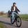Een aziatische dame fiets door de polder op een fietspad met haar speed pedelec.