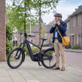 Meneer doet zijn helm op terwijl hij naast zijn speed pedelec staat.