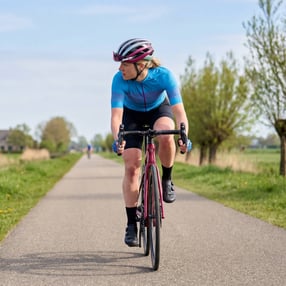 BLonde dame fiets op een racefiets over een fietspad in de polder.