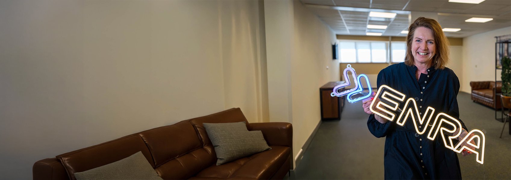 Directeur van ENRA Miranda de Bruin met een ENRA logo neon licht in haar handen.