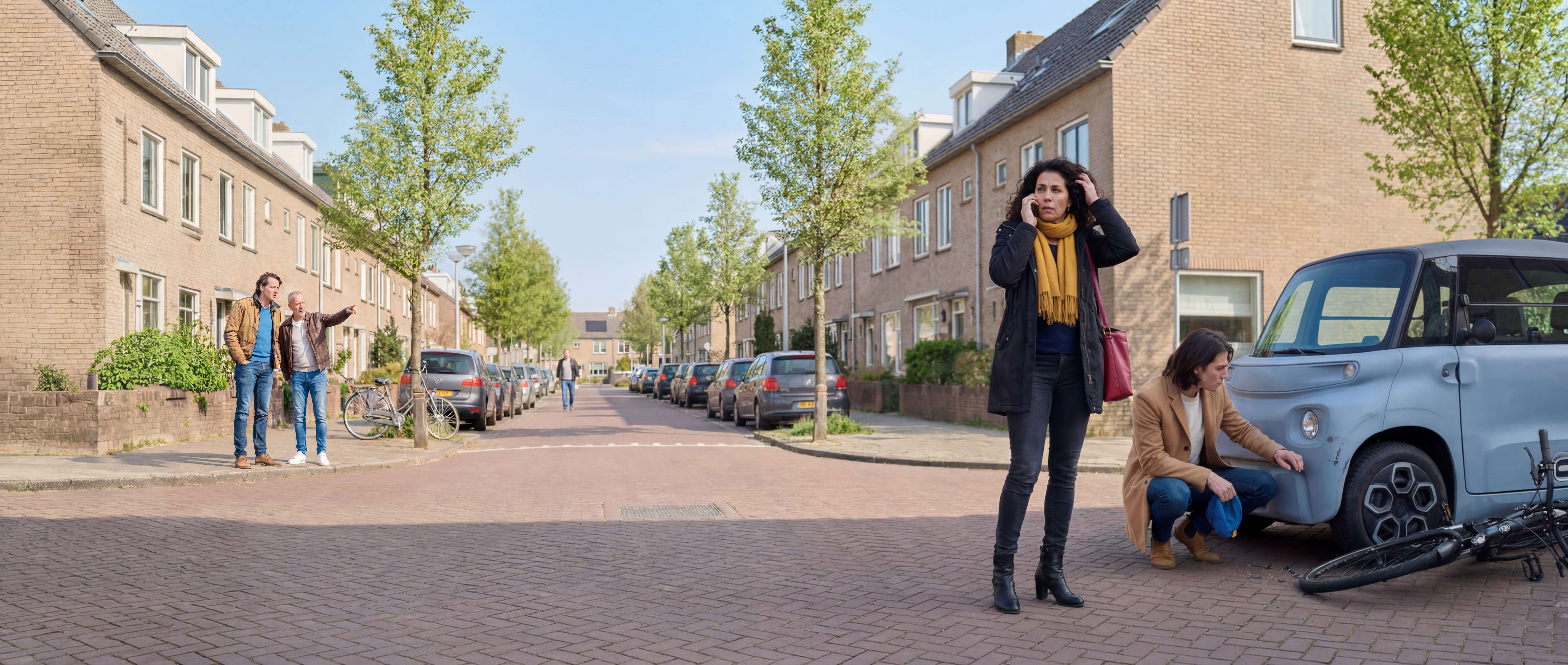 Mevrouw belt de pechhulp na een aanrijding met haar fiets. De brommobieler bekijkt zijn schade.