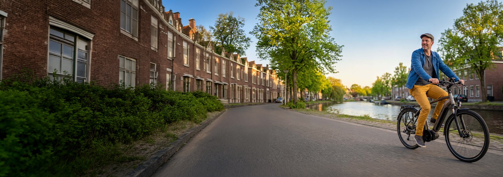 Man fietst langs het water in een nieuwbouw wijk in een stad op zijn e-bike.